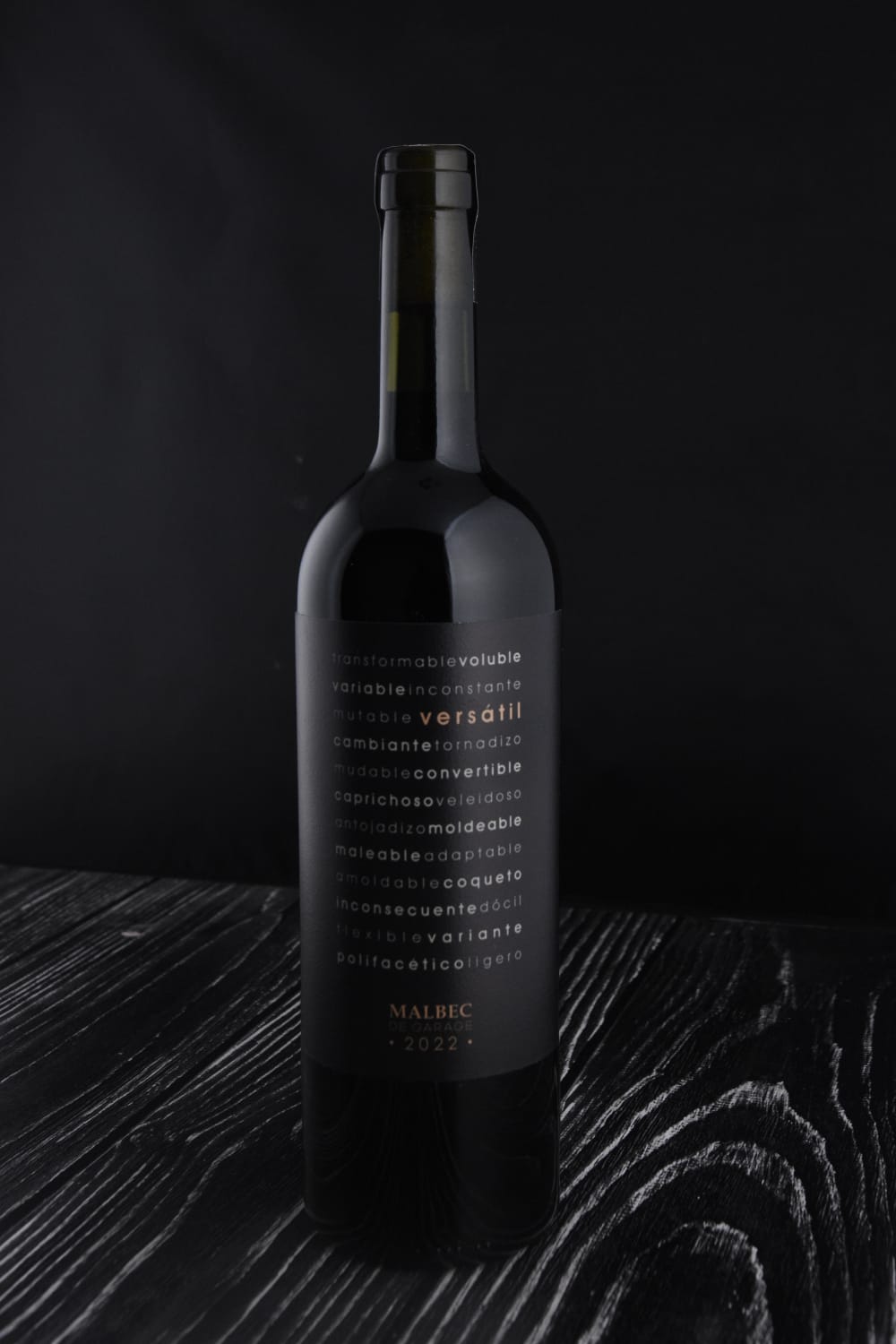 Malbec de Garage Versátil, etiqueta negra sobre madera oscura